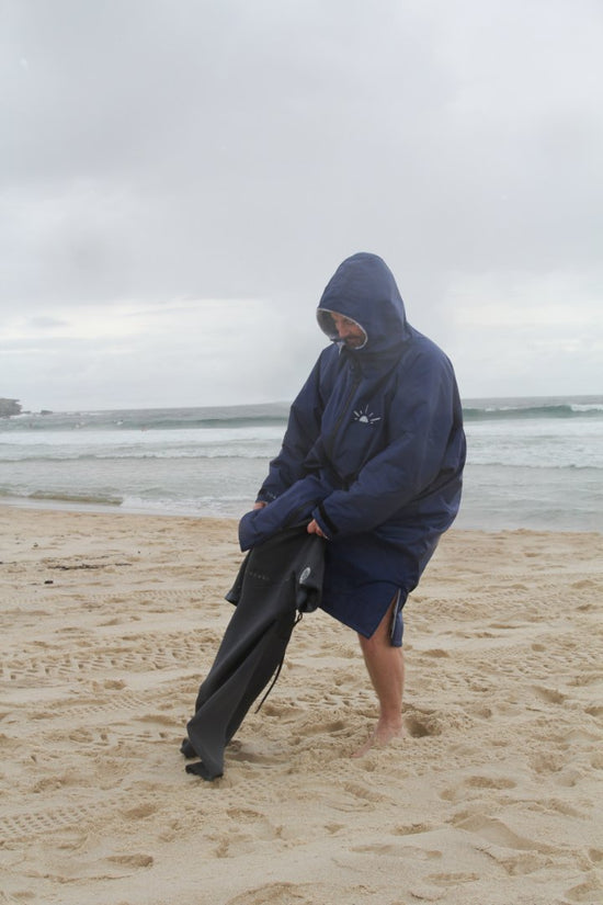 Changing into a wetsuit on the beach wearing Navy Toasty ultimate weatherproof changing jacket / robe