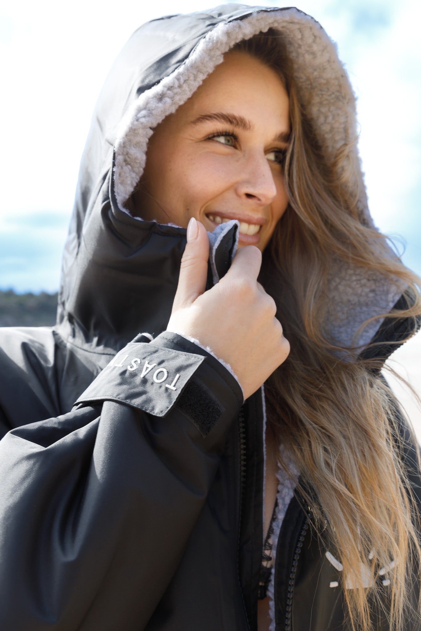 TOASTY Fleece lined weatherproof jacket in black worn by a girl on the beach