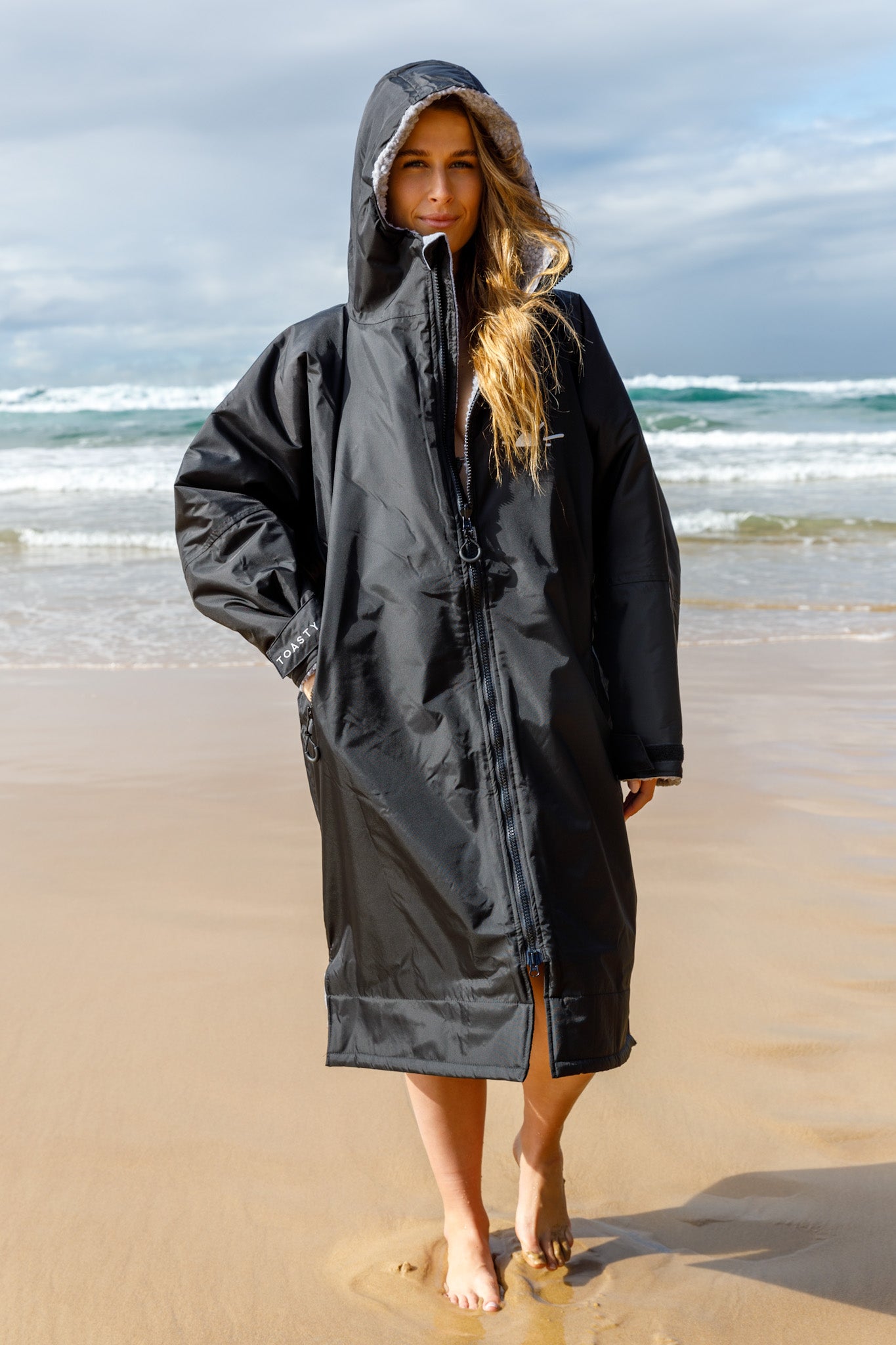 TOASTY Fleece lined weatherproof jacket in black worn by a girl on the beach